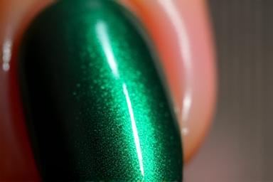 Effet oeil de chat magnétique sur des ongles verts émeraude